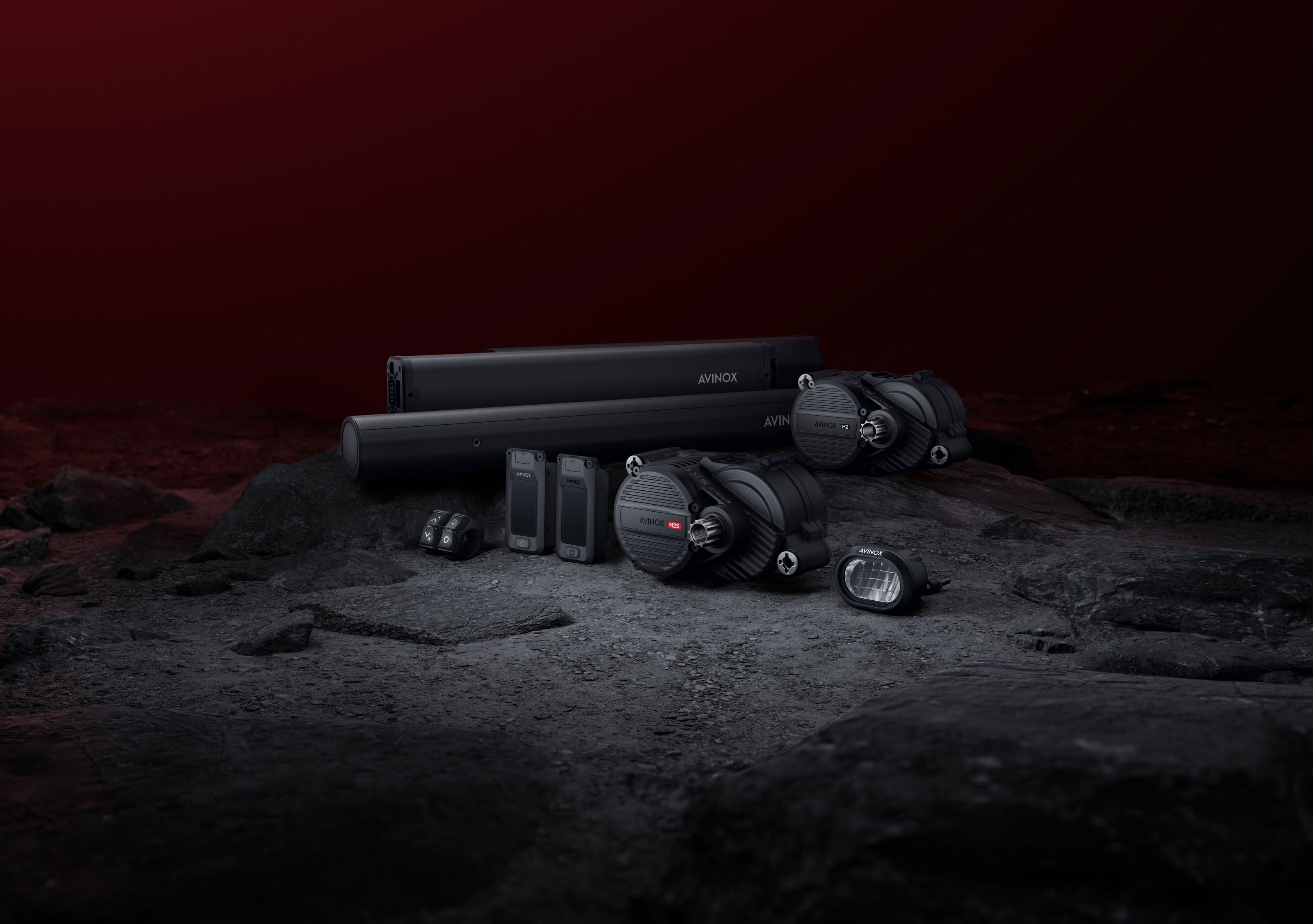 The Avinox M2S drive unit in front of the M2, with batteries, remotes and a light on dark rock